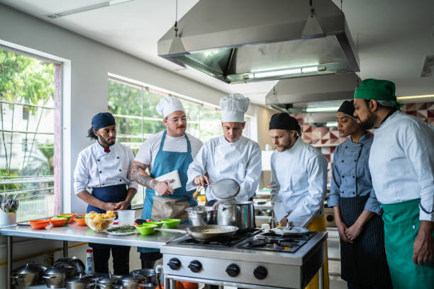 шеф-повар обучает студентов во время кулинарного класса - hat women chef occupation стоковые фото и изображения