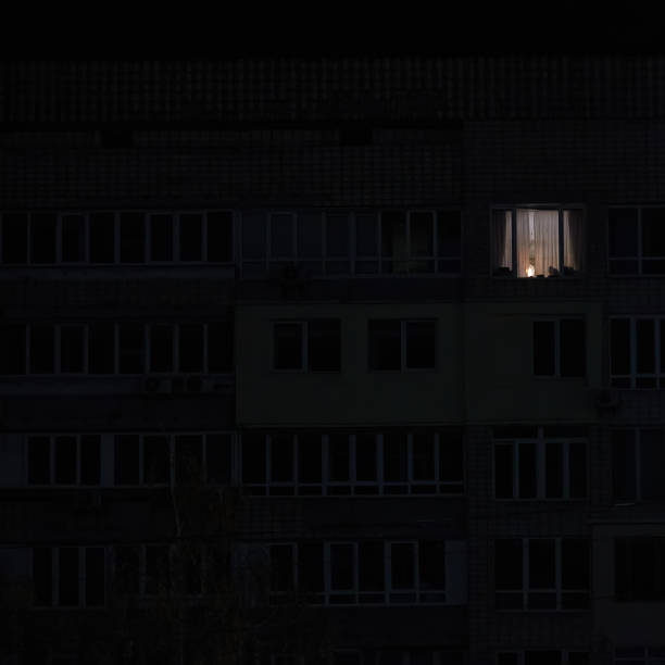 istock Light in one window in apartment multistorey building during the rolling blackout of electricity in a residential area of Kyiv after russian shelling. 1450132769