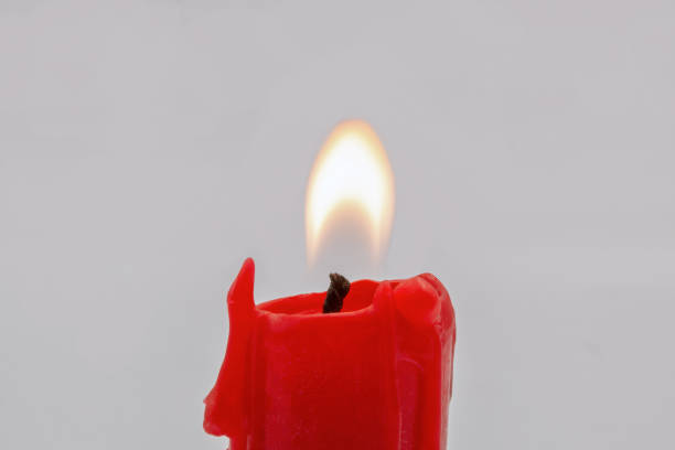 Two red candles burning in the dark. Predominant colors are red, yellow and black. The composition is at the left of an horizontal frame leaving useful copy space for text and/or logo at the right. High resolution 42Mp studio digital capture taken with Sony A7rII and Sony FE 90mm f2.8 macro G OSS lens