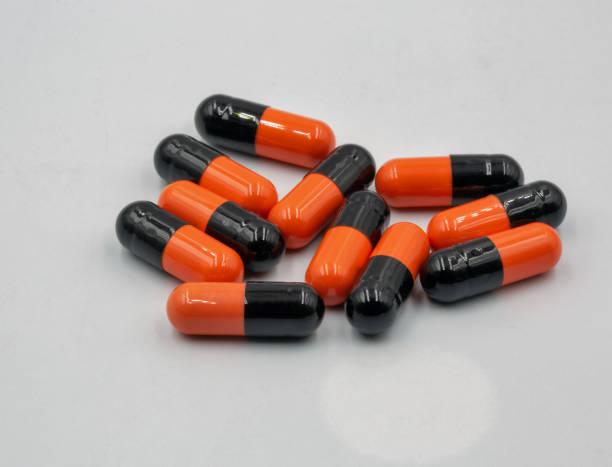 istock Medical capsules orange black closeup on white 1450143726