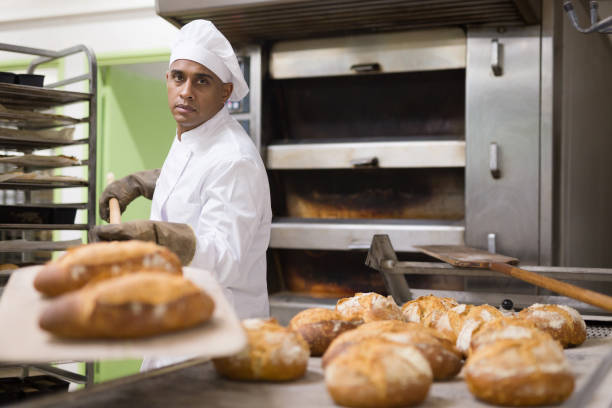 istock Man holding bread on peel in bakery 1450150709