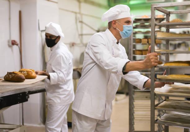 istock man in chefs uniform rolling trolley with bread in bakery during epidemic 1450150733