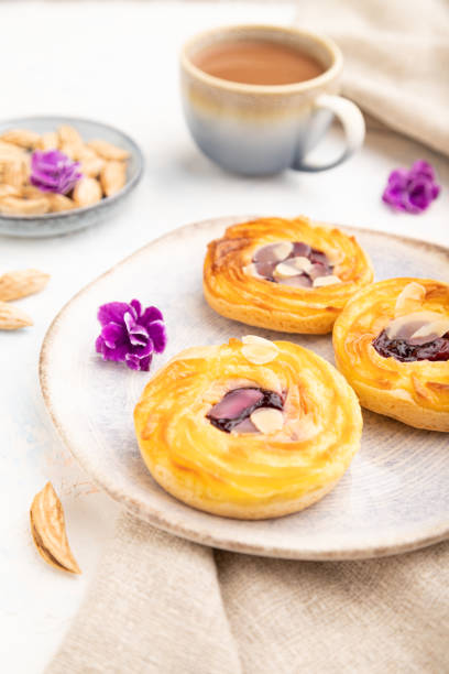 istock Small cheesecakes with jam and almonds with cup of coffee on a white concrete background. Side view, selective focus. 1450156967