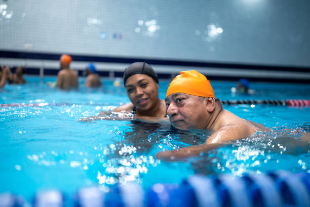 istock Disabled mature man learning to swim in the swimming pool 1450164765