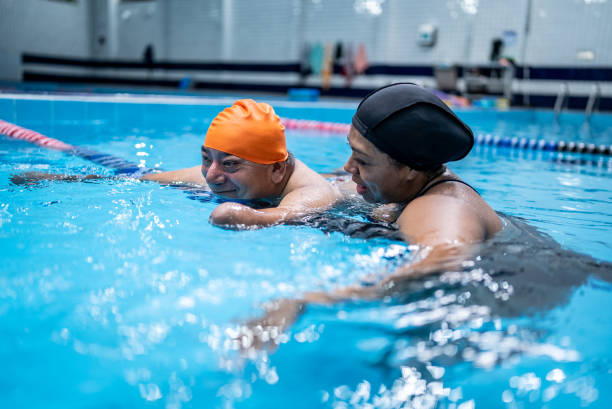 istock Disabled mature man learning to swim in the swimming pool 1450164791