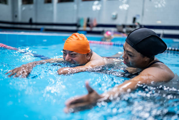istock Disabled mature man learning to swim in the swimming pool 1450164793