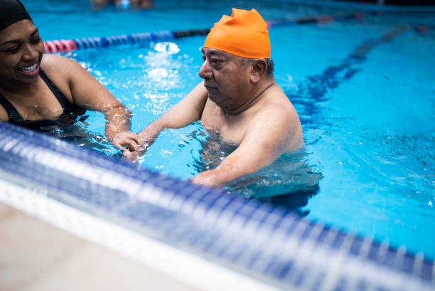 istock Disabled mature man learning to swim in the swimming pool 1450164810