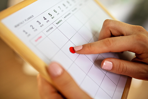 Unrecognizable woman planning out her week, using a desk planner with stickers