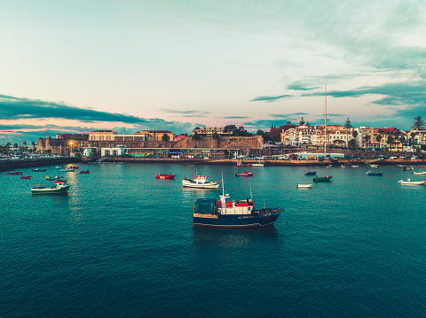 Aerial view of boats and ships in the sea near the port in Cascais, Portugal during sunset