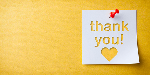 White Sticky Note With Thank You And Red Push Pin On Yellow Cardboard