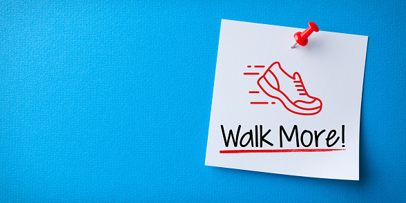 White Sticky Note With Walk More And Red Push Pin On Blue Background