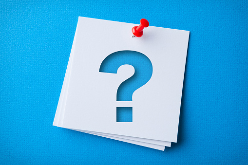 White Sticky Note With Question Mark And Red Push Pin On Blue Cardboard