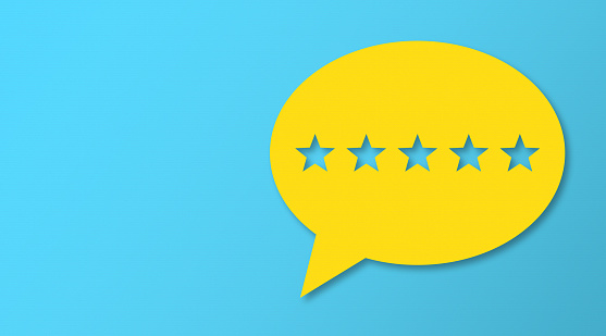 Feedback Concept - Yellow Chat Bubble With Cut Out Star Shapes On Blue Cardboard Background