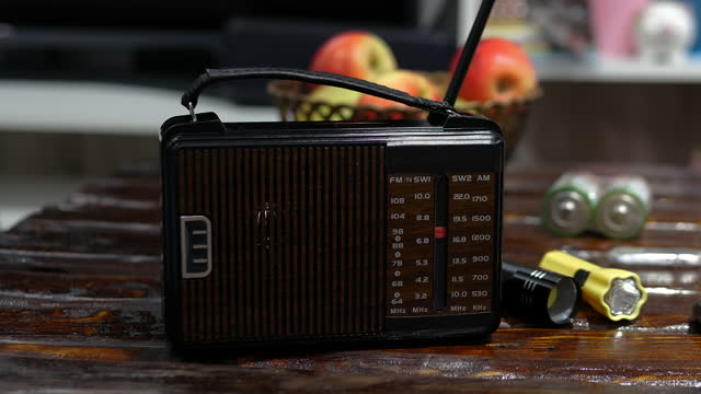 A man tunes a radio wave on the radio on an old wooden table. Antique receiver with antenna. Tune analog radio on a scale. A man listens to the news on an old radio. listening to music