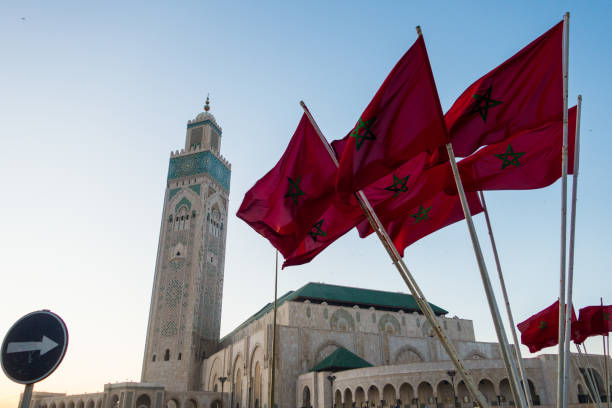 istock Hassan II mosque and a waving moroccan flags against sky 1450191819