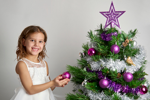 Happy a little girl decorating Christmas tree. Merry Christmas and Happy Holidays