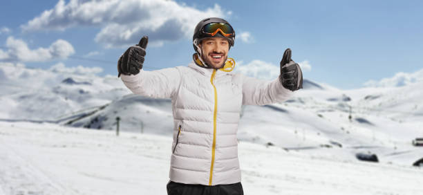 Cheerful male skier gesturing both thumbs up on a snowy mountain