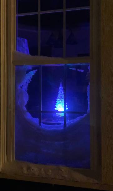 istock Christmas tree decoration glowing through a snowy window 1450204280