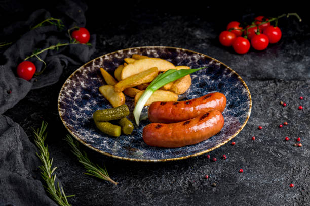 istock Fried hunter sausage with potato wedges on dark table 1450206195