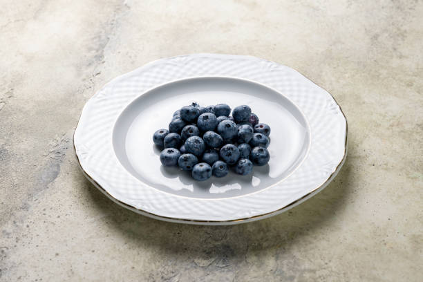 blueberry  on a white plate on stone table
