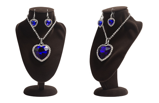 Luxurious jewelry set with blue heart shape diamonds: pendant and earrings on mannequin. Fashion jewelry, symbol of love, isolated. Present for woman for Christmas or other holidays.