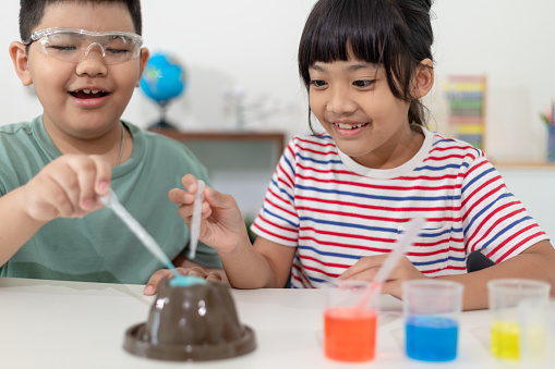 Kids repeating and observing a science lab project at home - the baking soda and vinegar volcano