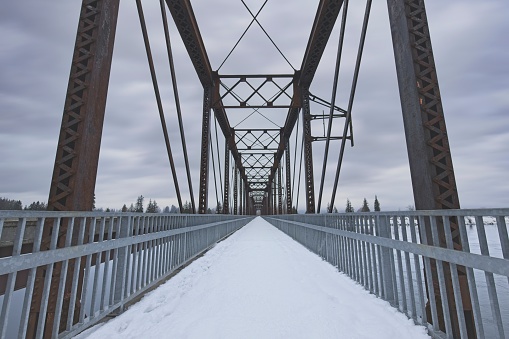 A snow covered walking path across an old bridge in north Idaho.