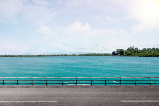 Asphalt road with lake and a blue sky background