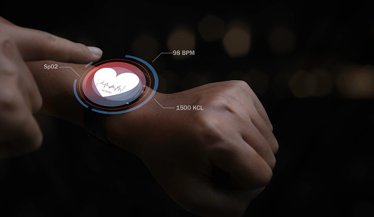 Smart watch technology checking heart rate with health app icon on the screen. Man using futuristic smart watch technology. Healthcare concept.