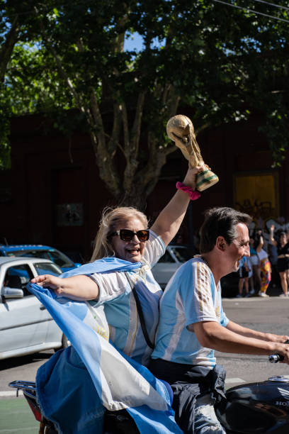 fans auf einem motorrad mit argentinischer flagge und einem pokal feiern argentiniens gewinn der fifa fussball-weltmeisterschaft 2022 in katar. - argentina qatar stock-fotos und bilder