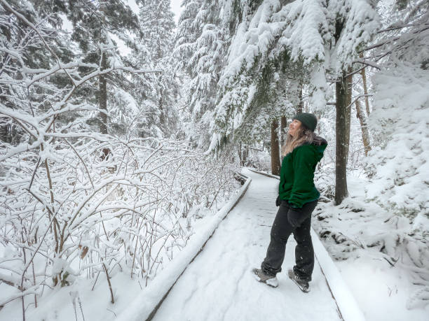 Multiracial Young Woman Enjoying Snowy Walk on Boardwalk Through Forest