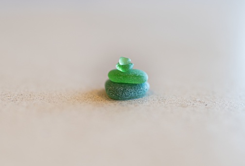 A closeup of green pieces of sea glass on beige surface