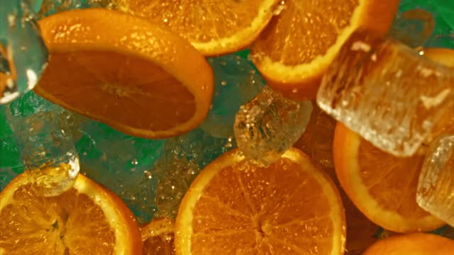 Juicy sweet orange and fly ice cube or water splash or pouring drops juice in super slow motion on 1000fps.Citrus orange slices and ice fall or explode on green chromakey in super slow motion 1000fps.