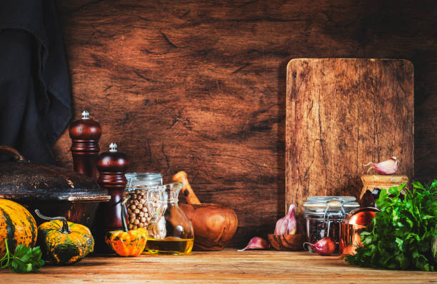 istock Cooking background. Rustic wooden kitchen table, cast iron pan, spice grinders, cutting board, spices and seasonings, storage jars. Copy space 1450242121
