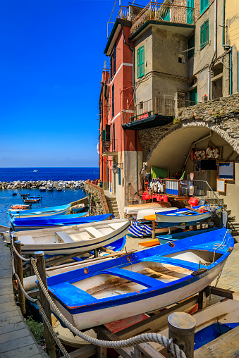 Daytime view onto the Mediterranean Sea with traditional boats and colorful houses in old town of Riomaggiore in Cinque Terre, Italy
