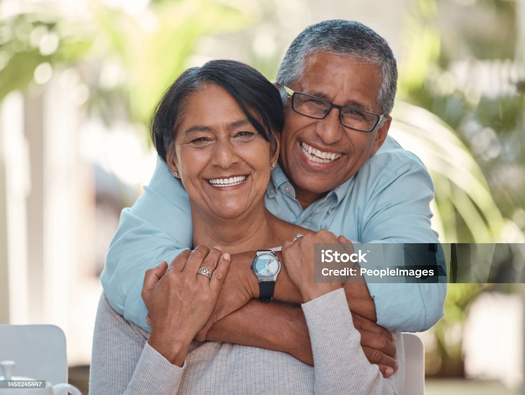 Portrait, elderly and couple bonding on a patio at home, hug, laugh and relax outdoors together. Love, retirement and happy seniors enjoying their relationship and bond, free time and fresh air Couple - Relationship Stock Photo