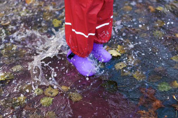 istock child splashing water in a puddle on a rainy day 1450246842