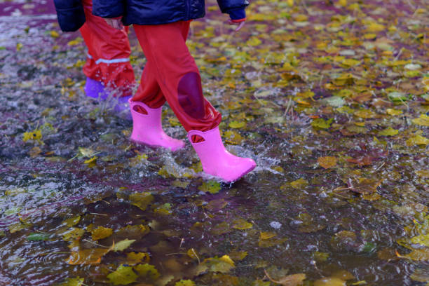 istock two children walking through a puddle of water on a rainy day 1450246849