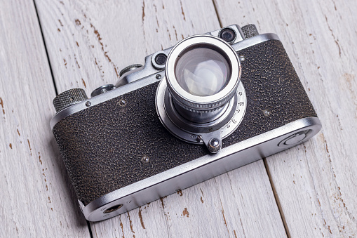 An old retro camera lies on a white wooden background.