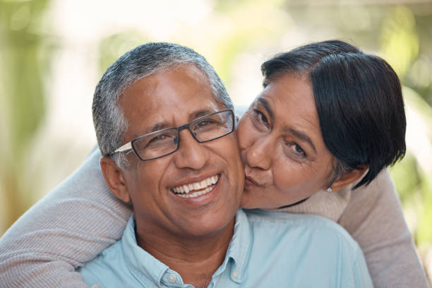 istock Love, kiss and happy senior couple sharing commitment, hug and affection while sitting together showing smile. Portrait of elderly indian man and woman enjoying retirement and free time to bond 1450248134
