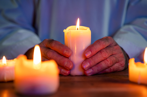 Man holding burning candle in dark room