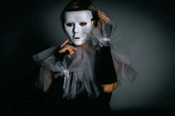 Woman in white theater mask and harlequin collar on black background. Fancy dress, masquerade clothes