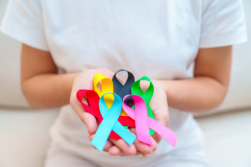 World cancer day, February 4. Hand holding blue, red, green, pink, black and yellow ribbons for supporting people living and illness. Healthcare and Autism awareness day concept