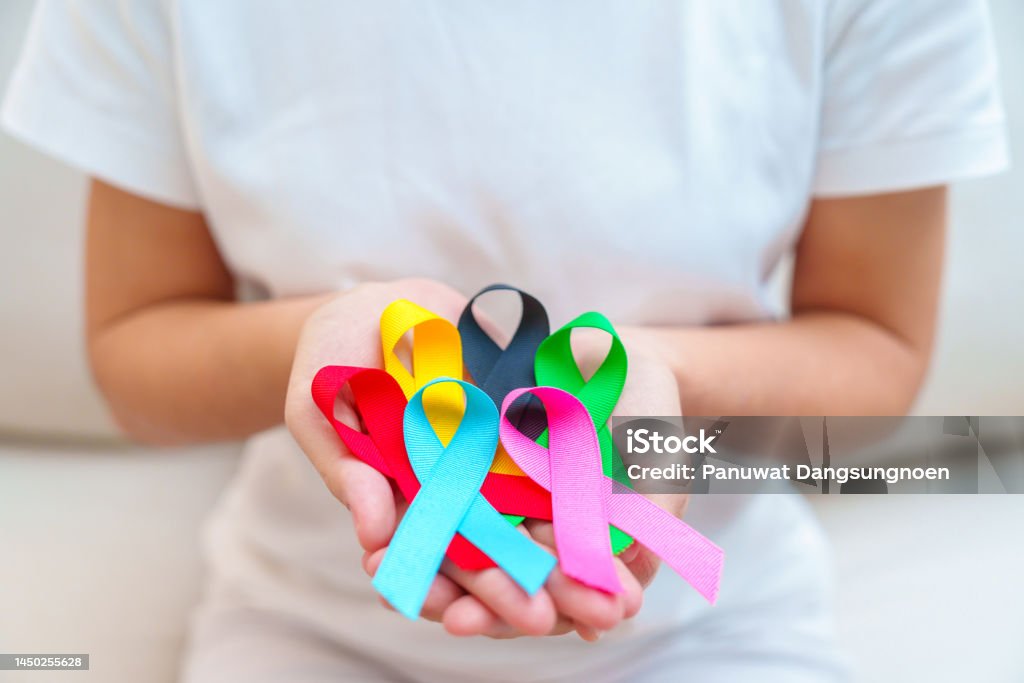 World cancer day, February 4. Hand holding blue, red, green, pink, black and yellow ribbons for supporting people living and illness. Healthcare and Autism awareness day concept Oncology Stock Photo