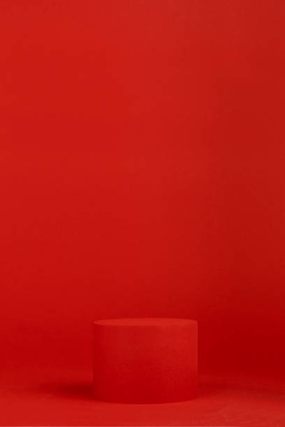 istock Red festive Christmas stage with one cylinder podium mockup on table for presentation cosmetic products, gifts, goods in simple modern style, copy space, vertical. Template for advertising, design. 1450260735