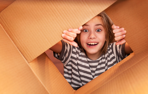 girl in a striped T-shirt opens a cardboard box