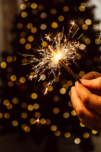 bright festive sparkler in mens hands on the background of a christmas tree. the concept of new year holidays and weekends. closeup. selective focus.