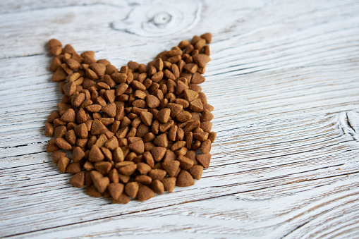 Dry pet food on a white wooden background, close-up.