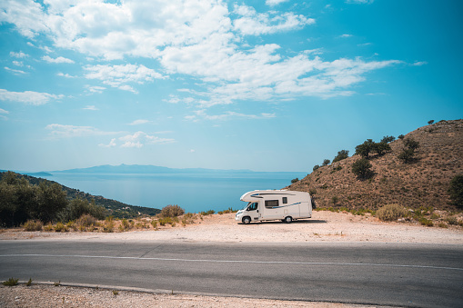 Camper car parked next to the seaside next to the road. Idyllic scene at Mediterranean coast.