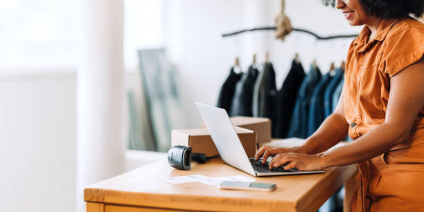 istock Happy online store owner using a laptop in her shop 1450267022